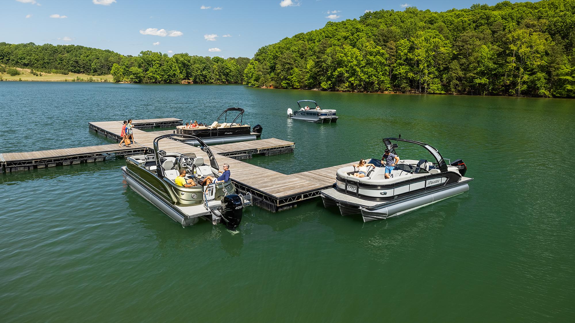 Family of Manitou pontoons docked at the landing of a lake.