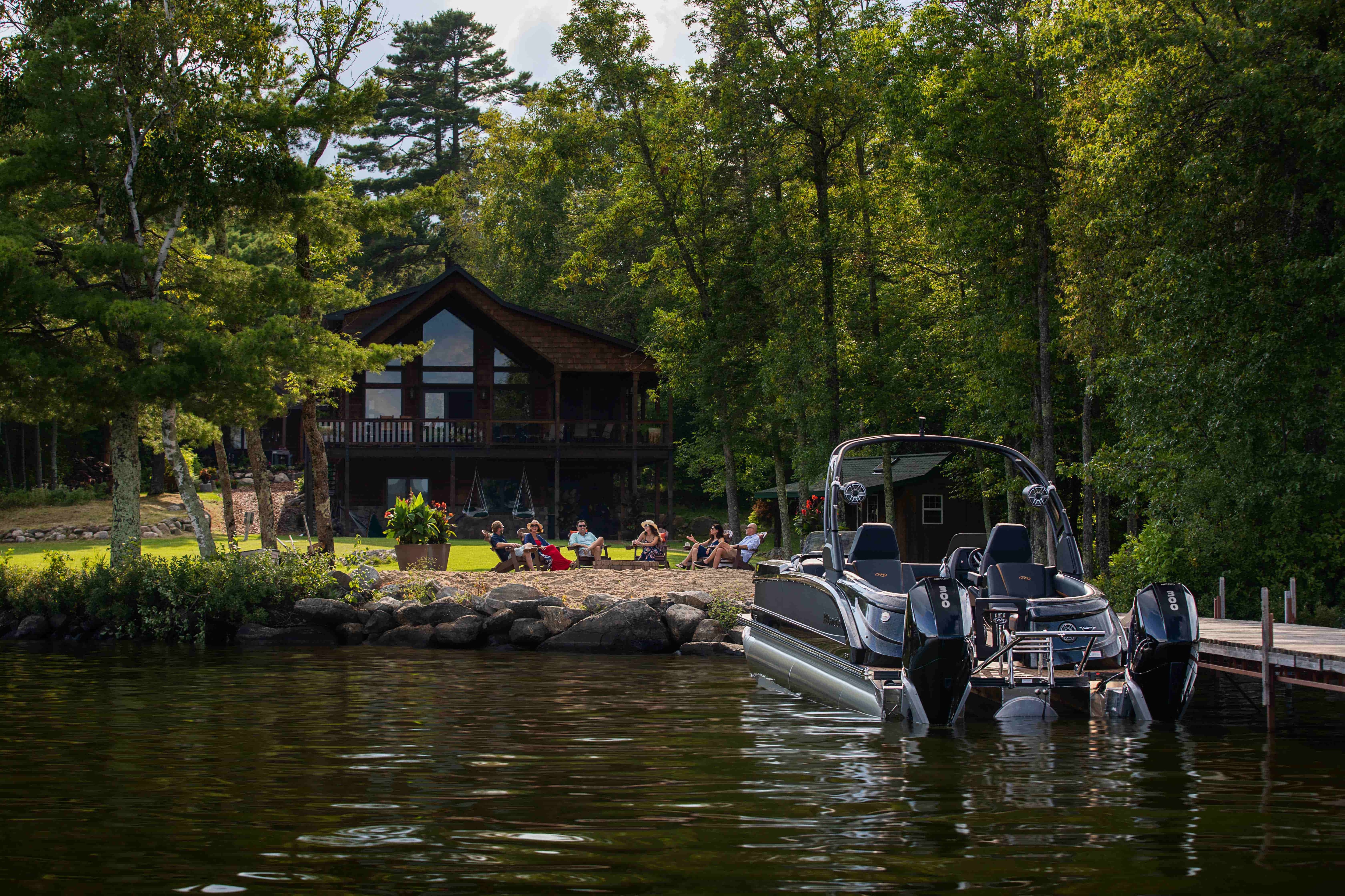 Manitou XT Pontoon Boat docking near a house