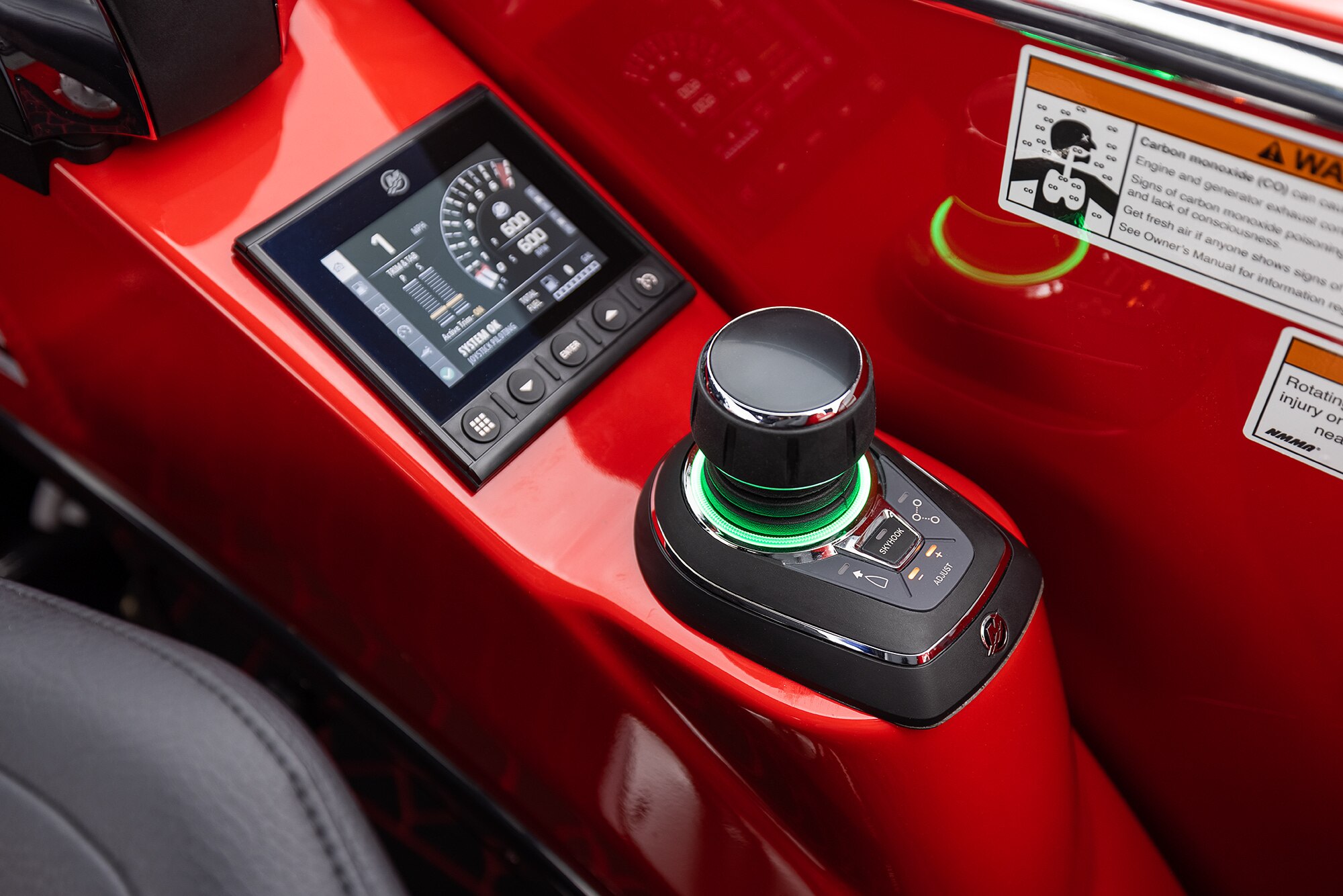 Close up of a driving joystick of a 2022 red Manitou XT pontoon boat