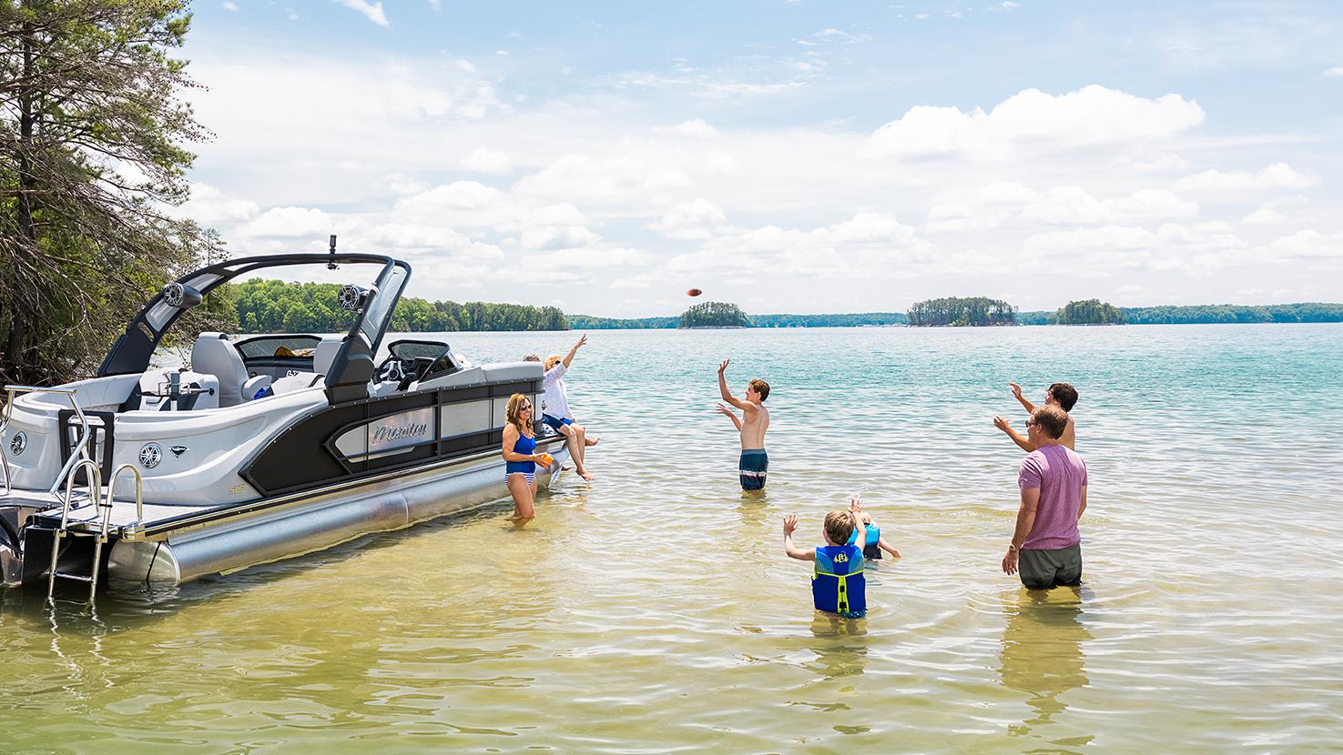 Famille jouant dans l'eau à côté de leur bateau ponton Manitou LX sport 2022