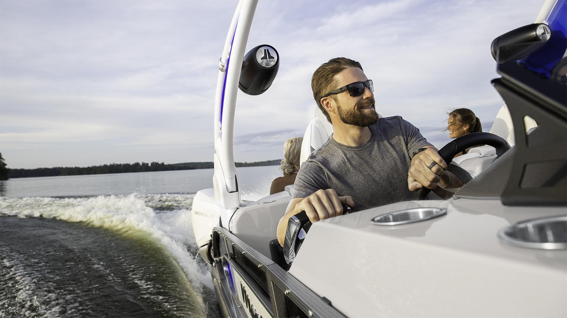 Man driving his Manitou pontoon boat on a lake