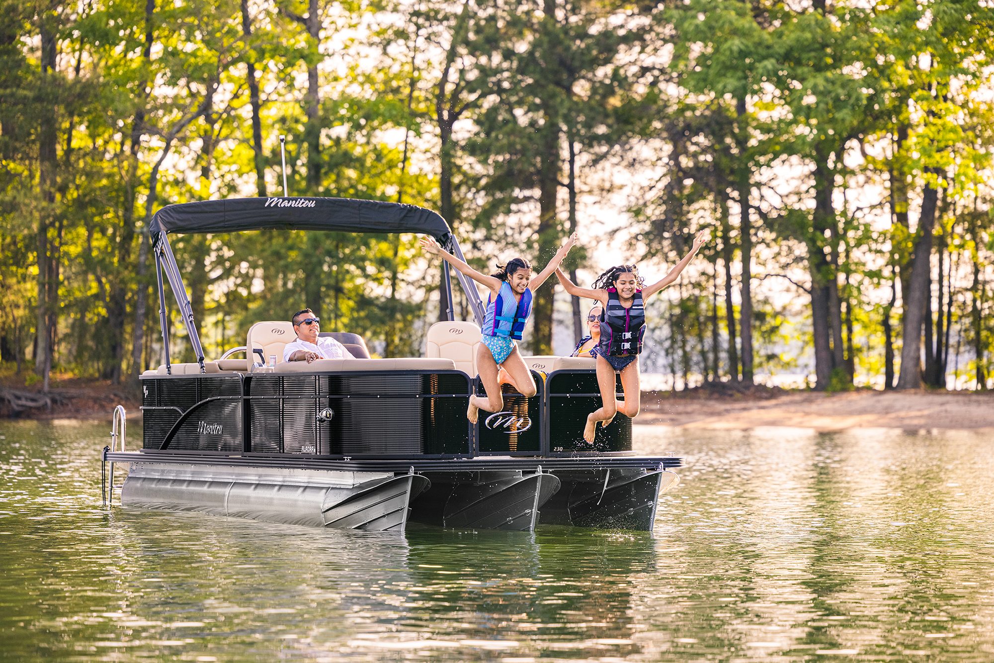 Girls jumping in the water from a Manitou Aurora LE Pontoon Boat