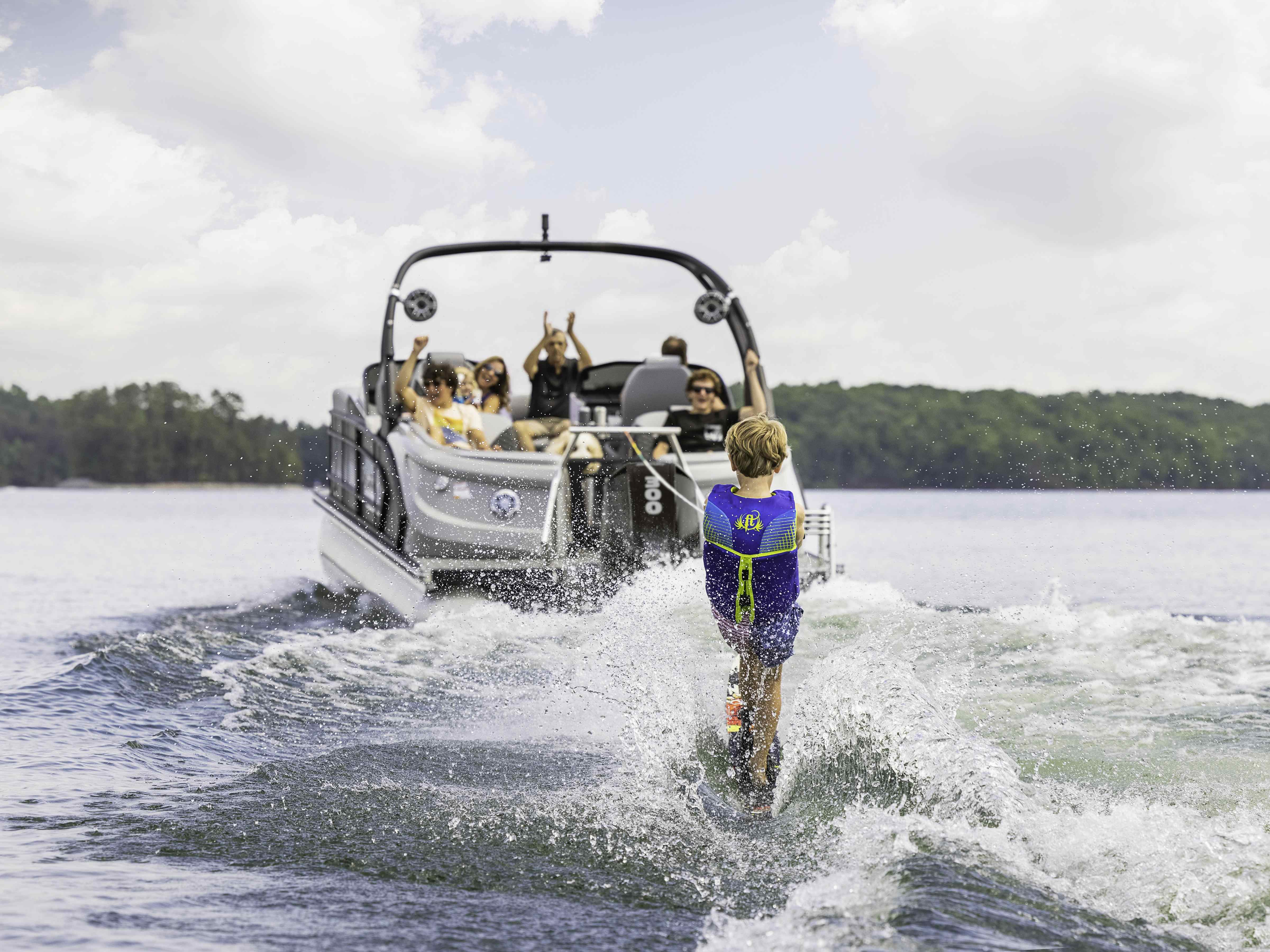 Manitou Pontoon Boat pulling a kid for a wakeboard ride