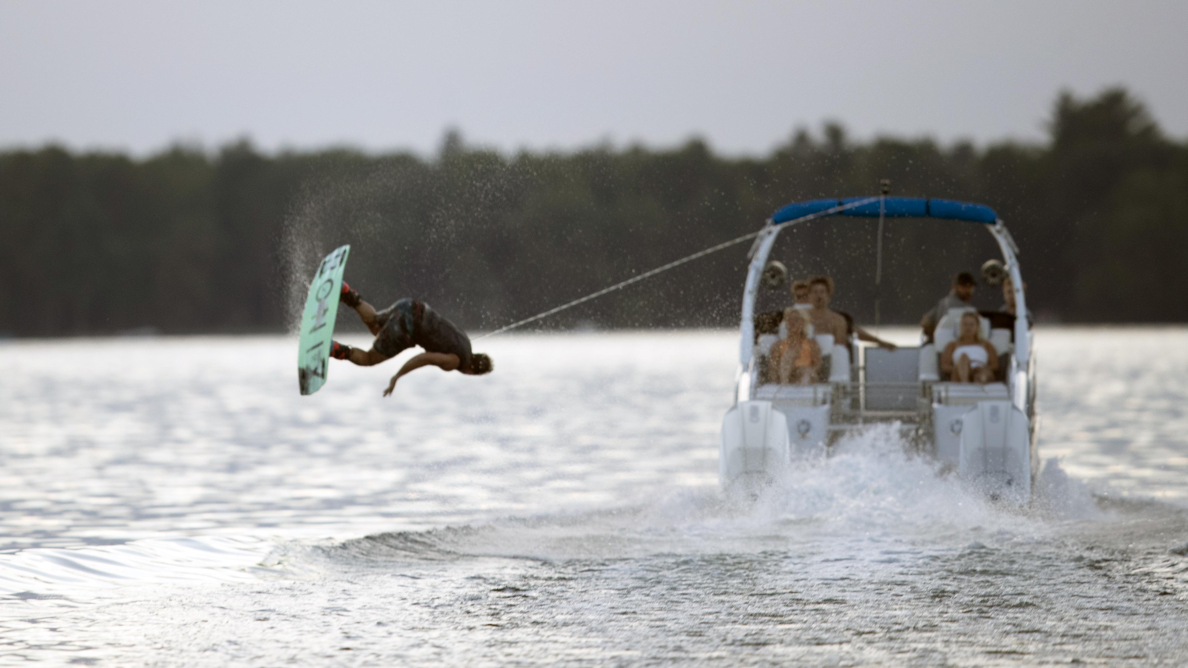 Wakeboarder jumping a wave behind a 2022 Manitou LX Pontoon Boat