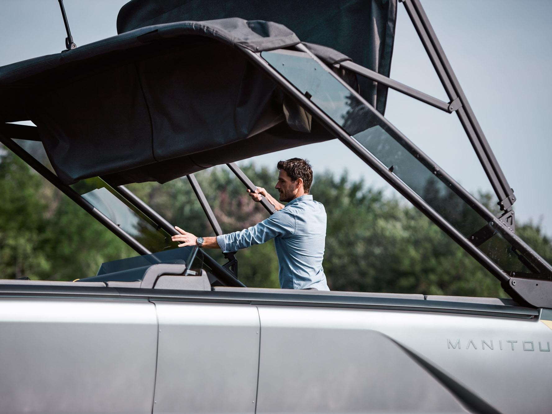 Man folding the Bimini top on his 2023 Manitou Explore pontoon