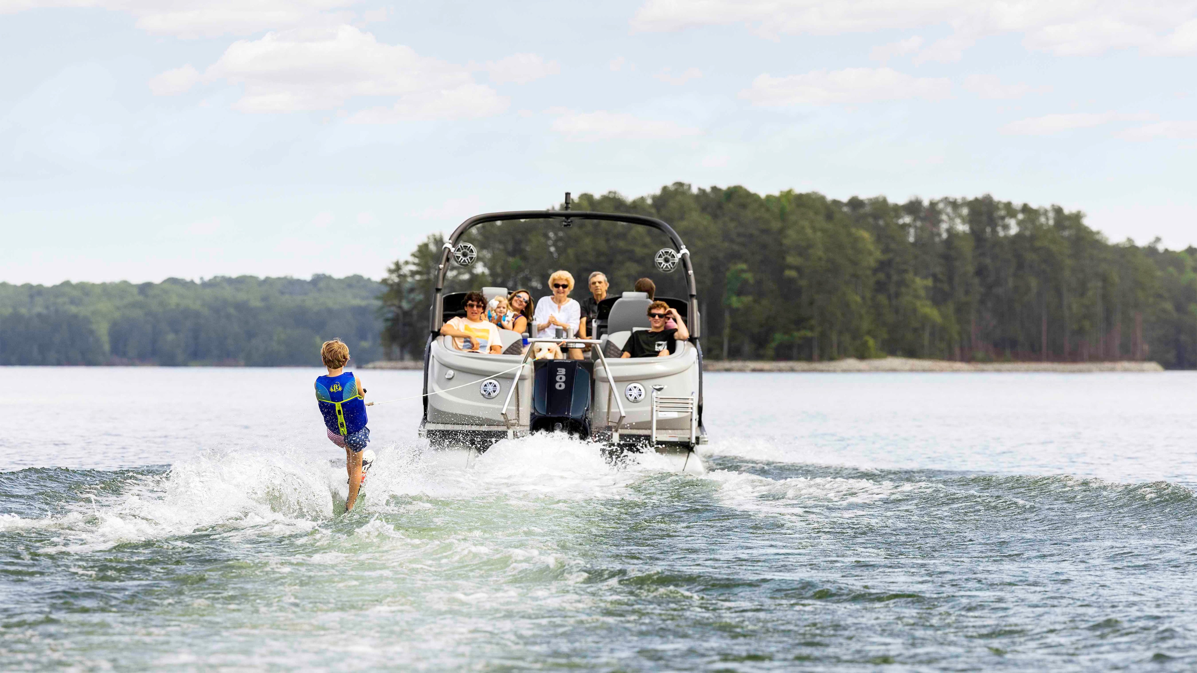 Manitou Pontoon Boat pulling a kid for a wakeboard ride