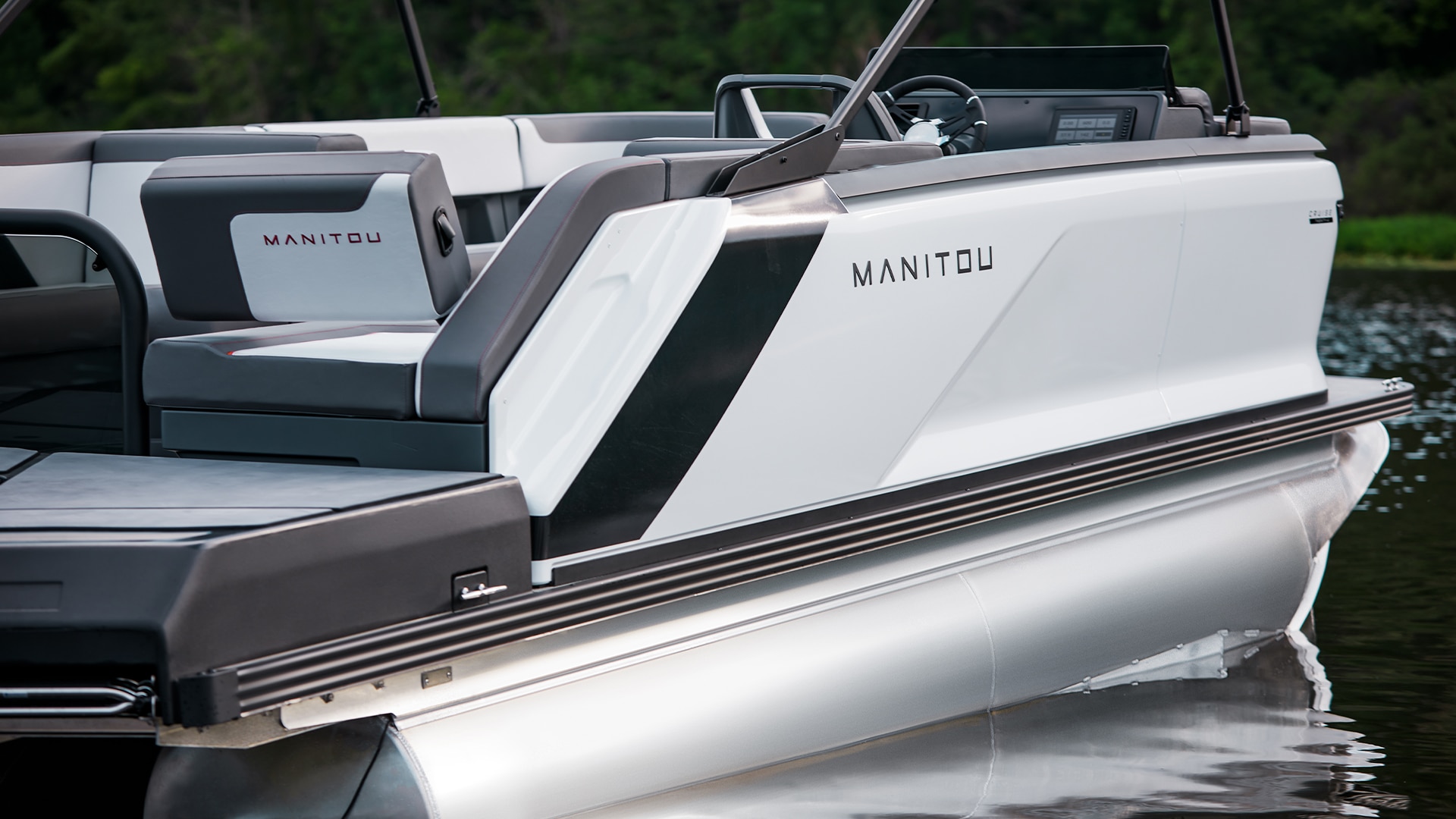 Sideview of a 2023 Manitou Cruise pontoon boat idle on water 