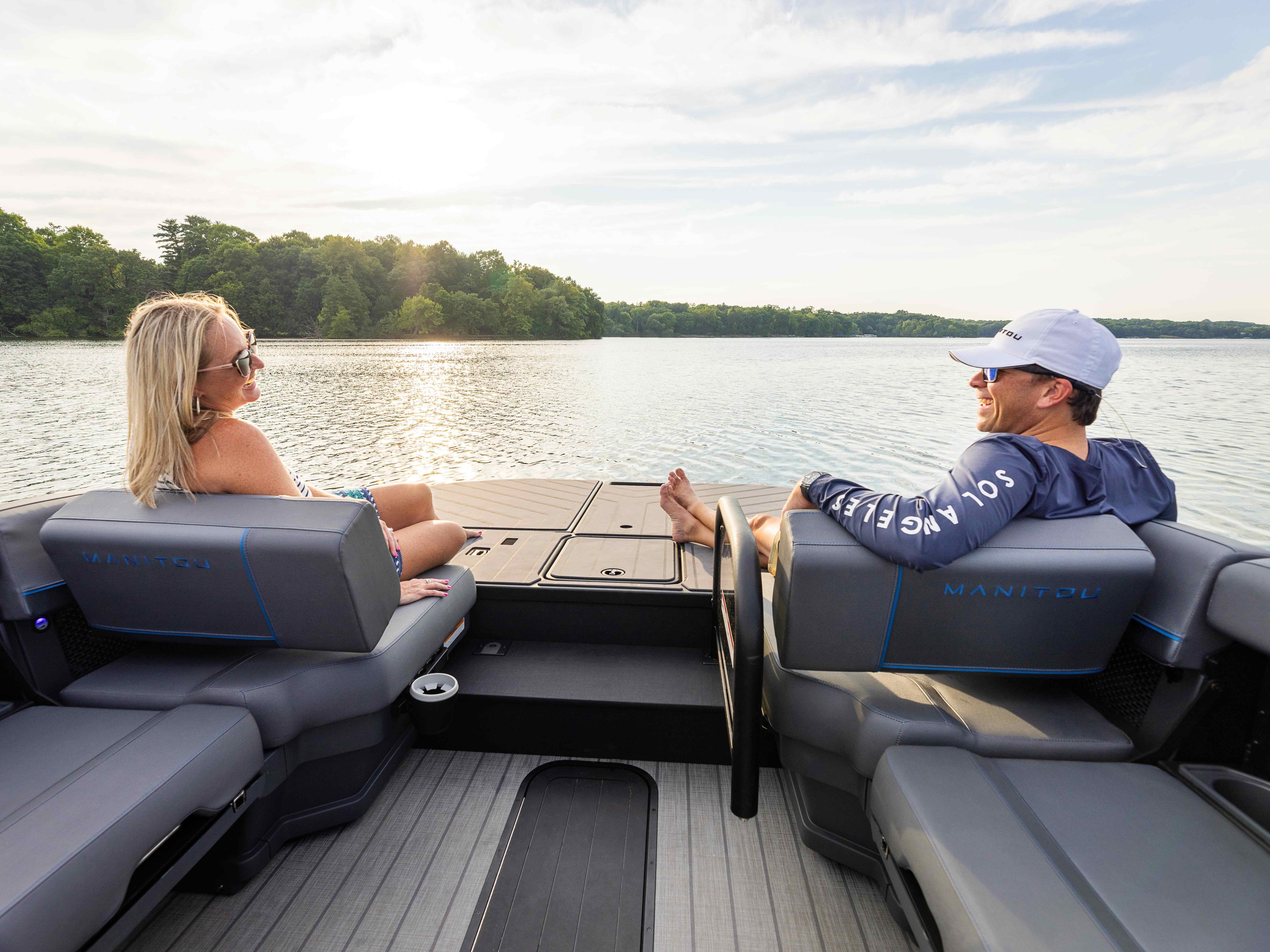 Two people sitting next to the MAX Deck platform on the 2024 Manitou Explore pontoon