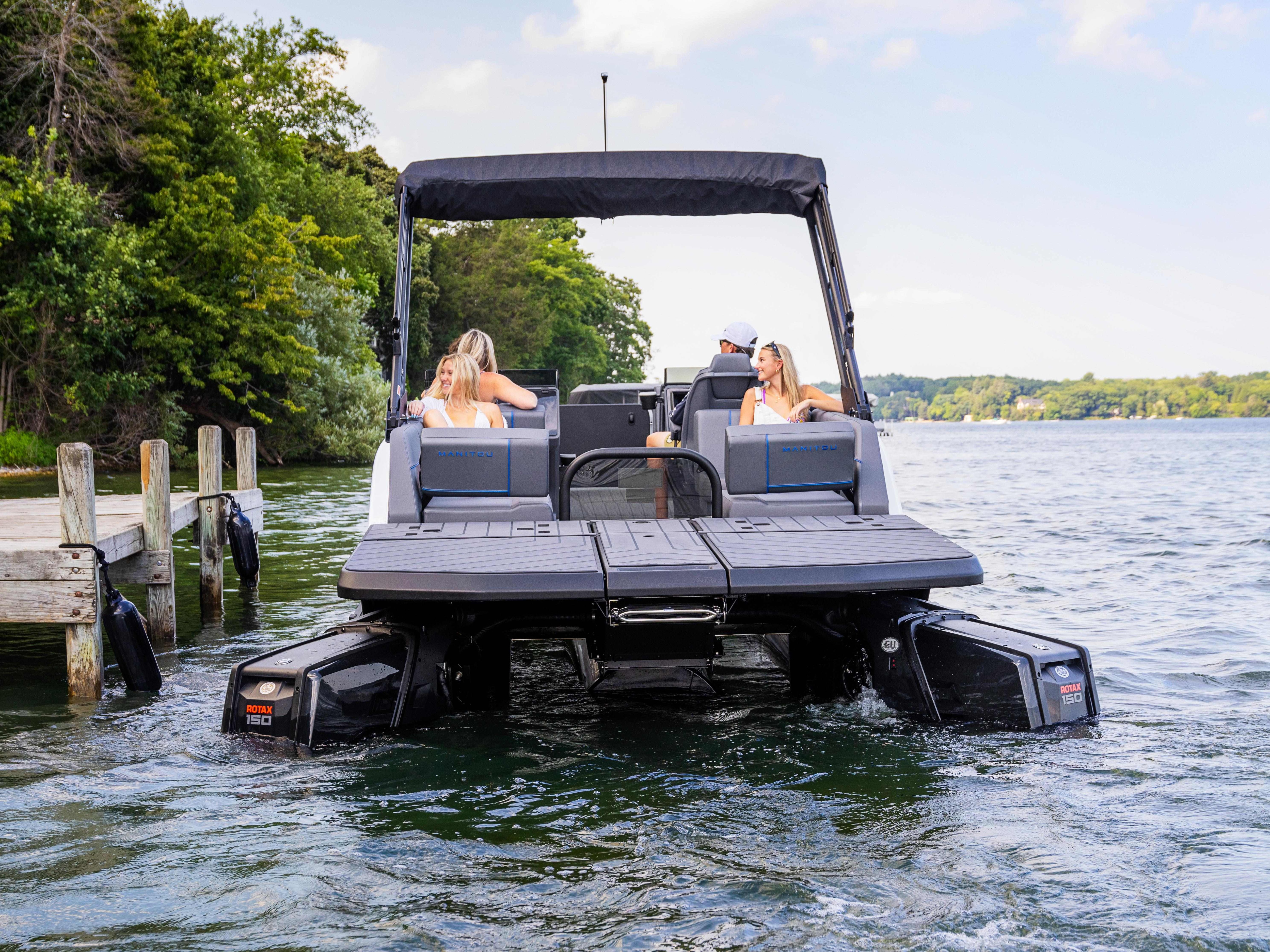 Friends sitting in a docked 2024 Manitou Explore Switchback pontoon