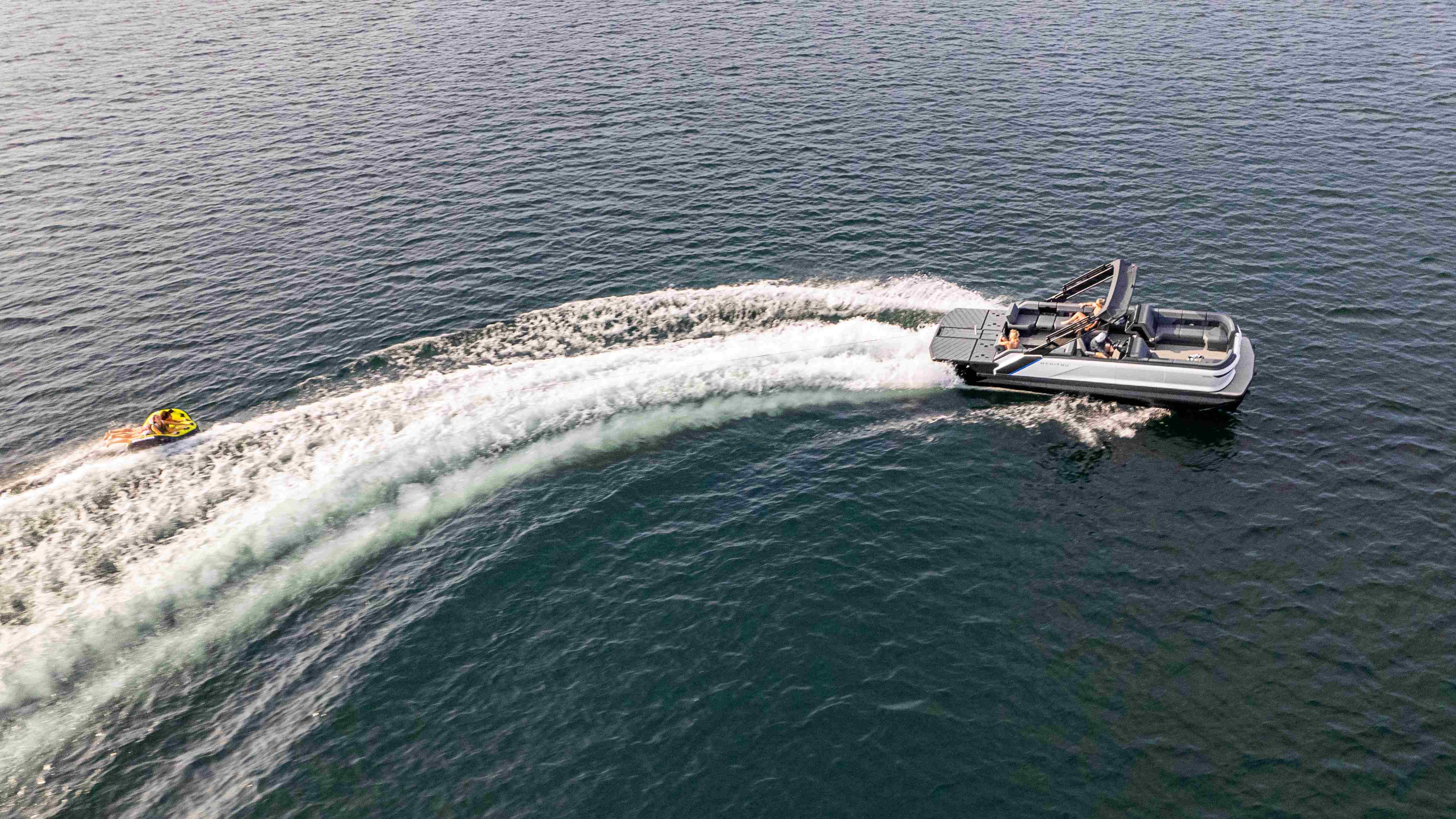 Manitou pontoon with water skier behind