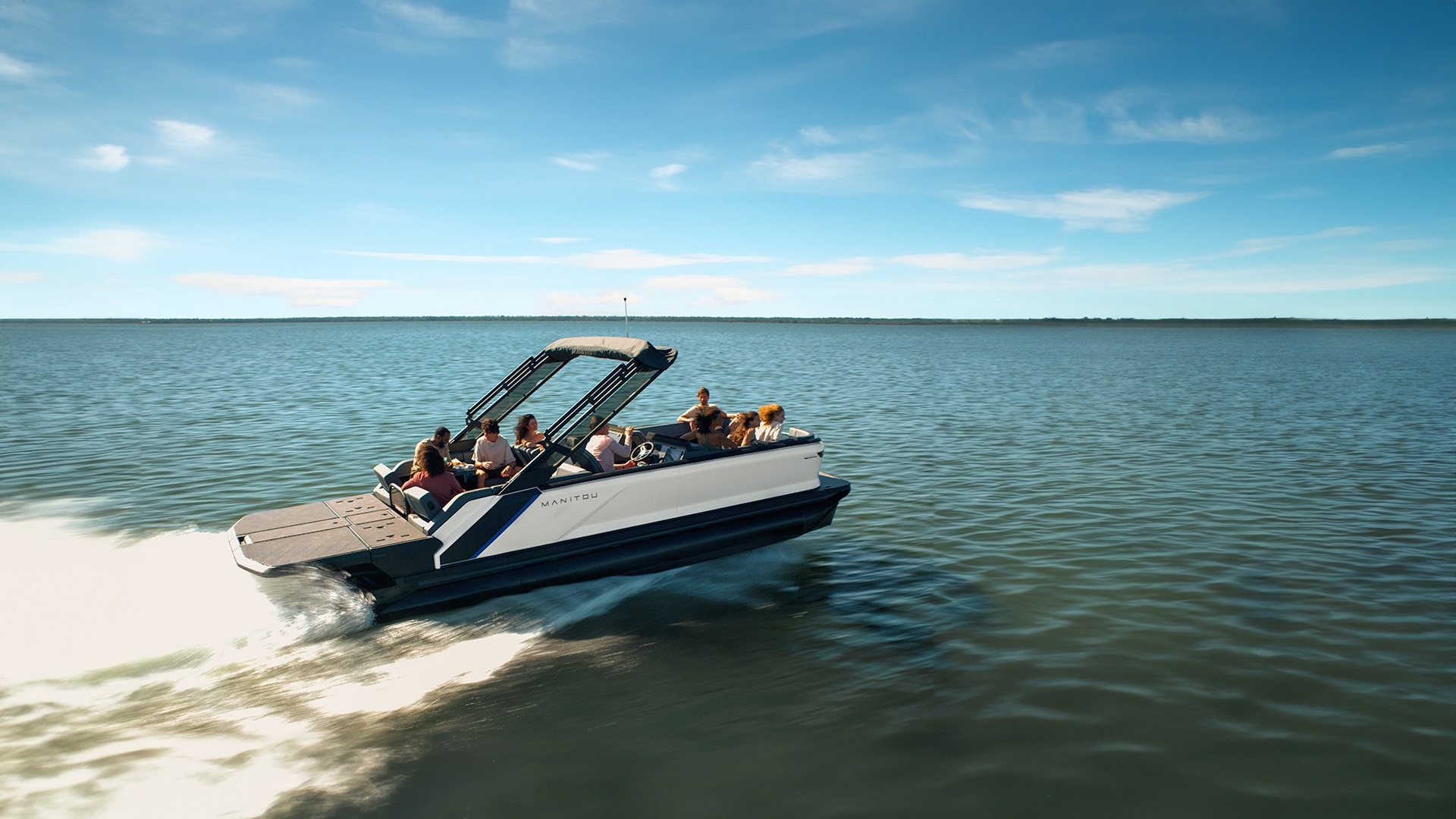 A white Manitou Explore 2024 pontoon boat cruising a lake at top speed