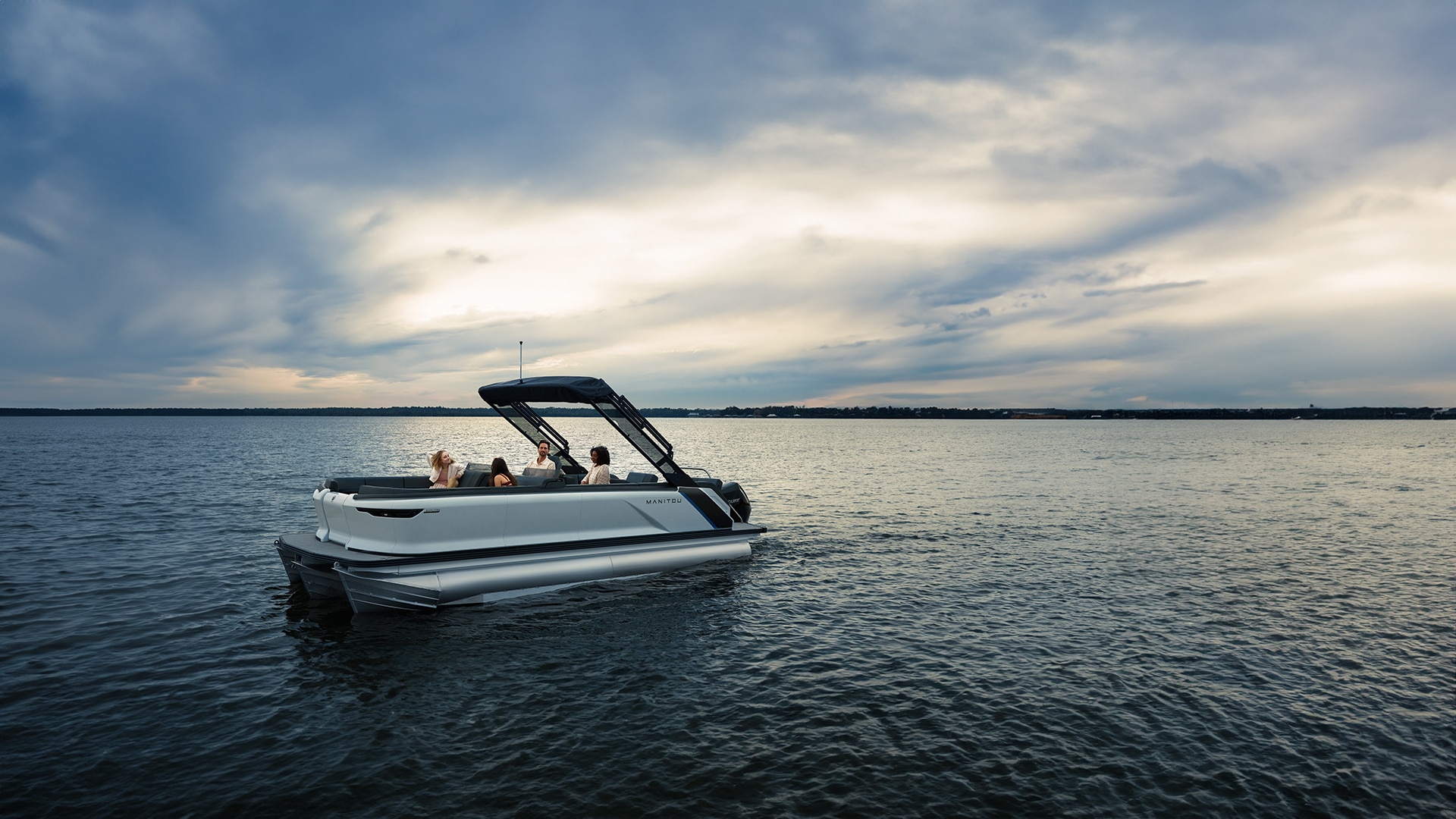Side view of a group of 4 people on a Manitou 2024 recreational pontoon boat.