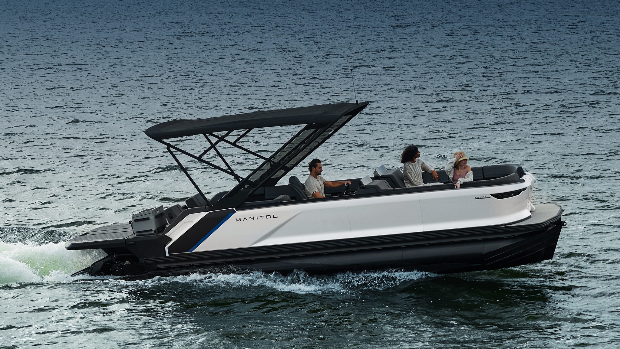 Small family on the water aboard a white Manitou pontoon boat